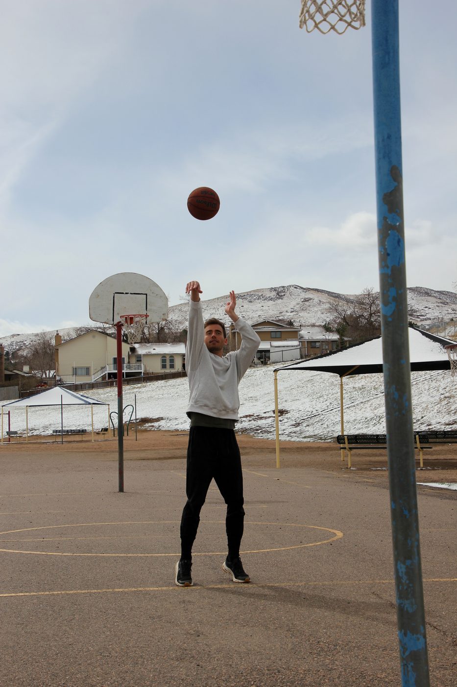 Kyle Wisniewski shooting at an outdoor hoop in Golden, Colorado with snow on the foothills, 2025